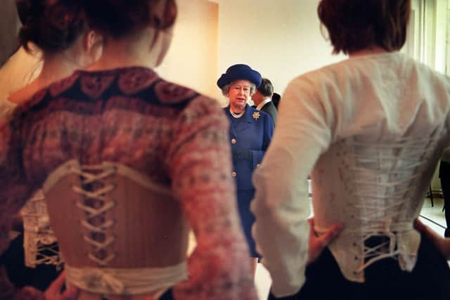 Queen Elizabeth II admires costumes worn by students from the drama school RADA, ahead of their performance of Oklahoma at the Lyceum Theatre