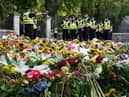 Police officers arrive at the gates of Balmoral in Scotland where flowers and tributes have been laid by members of the public following the death of Queen Elizabeth II. The Queen's coffin will be transported on a six-hour journey from Balmoral to the Palace of Holyroodhouse in Edinburgh, where it will lie at rest. Picture date: Sunday September 11, 2022.