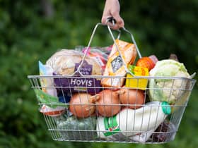 A woman holds a shopping basket of groceries.