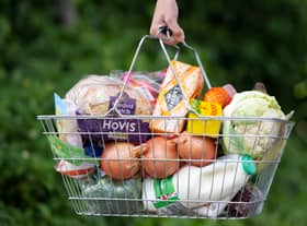 A woman holds a shopping basket of groceries.