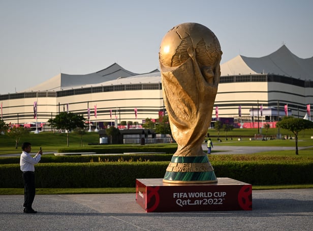 <p>A man takes a picture of a FIFA World Cup trophy replica in front of the Al-Bayt Stadium in al-Khor on November 10, 2022, ahead of the Qatar 2022 FIFA World Cup football tournament. (Photo by Kirill KUDRYAVTSEV / AFP) (Photo by KIRILL KUDRYAVTSEV/AFP via Getty Images)</p>