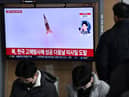 A man watches a television screen showing a news broadcast with file footage of a North Korean missile test, at a railway station in Seoul on December 31, 2022