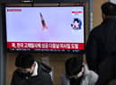 A man watches a television screen showing a news broadcast with file footage of a North Korean missile test, at a railway station in Seoul on December 31, 2022