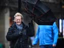 A woman battles to keep control of her umbrella as she walks through a rain shower in Glasgow.