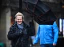 A woman battles to keep control of her umbrella as she walks through a rain shower in Glasgow.