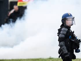 A French gendarme stands next to smoke during a demonstration as part of a national day of strikes and protests, a week after the French government pushed a pensions reform through parliament without a vote, using the article 49.3 of the constitution, in Nantes, western France, on March 23, 2023