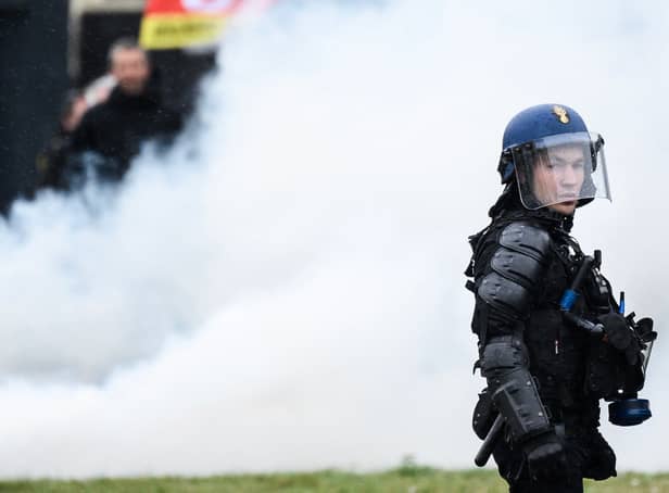 A French gendarme stands next to smoke during a demonstration as part of a national day of strikes and protests, a week after the French government pushed a pensions reform through parliament without a vote, using the article 49.3 of the constitution, in Nantes, western France, on March 23, 2023
