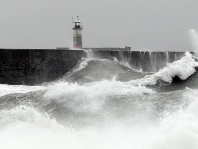 Waves crash over the breakwater by Newhaven Lighthouse as Storm Barra passes through Newhaven, southern England on December 7, 2021. (Photo by GLYN KIRK / AFP) (Photo by GLYN KIRK/AFP via Getty Images)