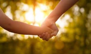 Mother or older sister hold a child's hands