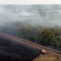 In this aerial view, a fire engine is seen on the field while smoke rises from the trees on July 19, 2022 in Blidworth, England