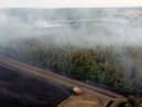 In this aerial view, a fire engine is seen on the field while smoke rises from the trees on July 19, 2022 in Blidworth, England