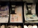 An open cash register containing pound coins and notes is pictured in a convenience store in London