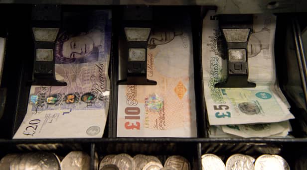 An open cash register containing pound coins and notes is pictured in a convenience store in London
