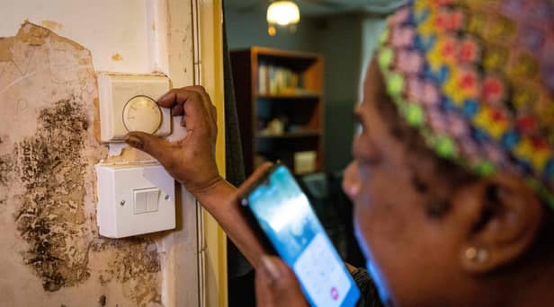 Doreen Thompson adjusts her thermostat at her home as she limits her use of heating to keep up with her increasing energy bills, at her home in south London.