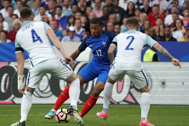 France’s midfielder Kylian Mbappe (C) runs with the ball towards England’s defender Kieron Trippier (R) and England’s midfielder Phillip Jones (L) during the international friendly football match between France and England at The Stade de France Stadium in Saint-Denis near Paris on June 13, 2017. / AFP PHOTO / Thomas SAMSON