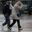 People walk in rain and high winds.
