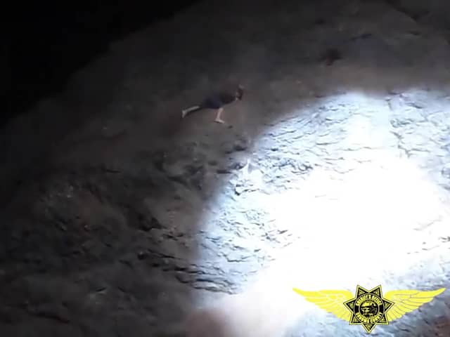 Thermal imaging footage shows man clinging onto cliff face.