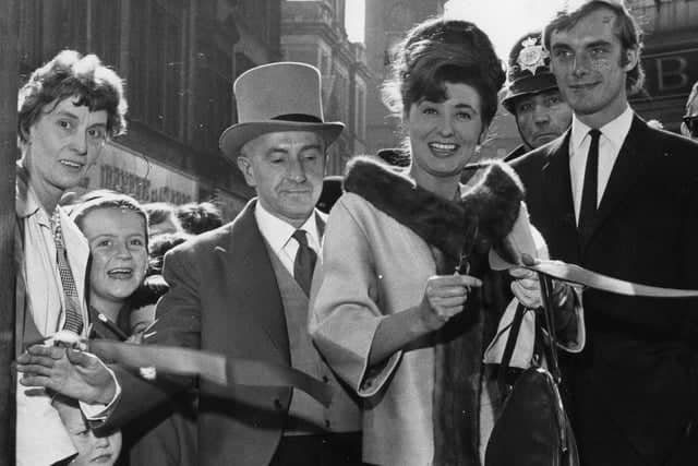 Actress Pat Phoenix, also known as Elsie Tanner of Coronation Street, cuts the tape to officially open Tops Clothing Store in King Street. With her is actor Roger Adamson, who also appeared in Coronation Street. This one takes us back to 1964.