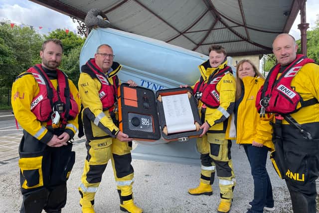 The Tynemouth RNLI crew holding the 200th anniversary scroll in front of the South Shields Lifeboat Memorial. Photo: National World.