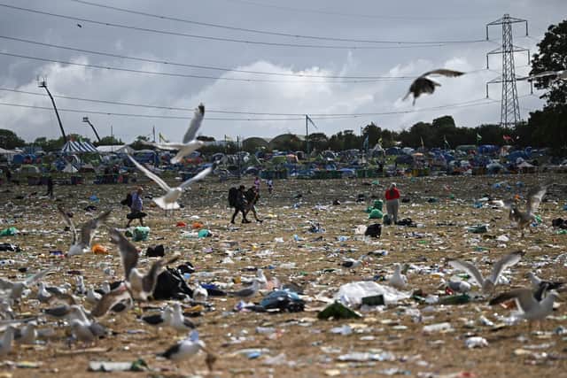 Festival goers carry their belongings as they walk across a field covered in litter at the end of Glastonbury festival in the village of Pilton in Somerset, southwest England, on June 26, 2023.