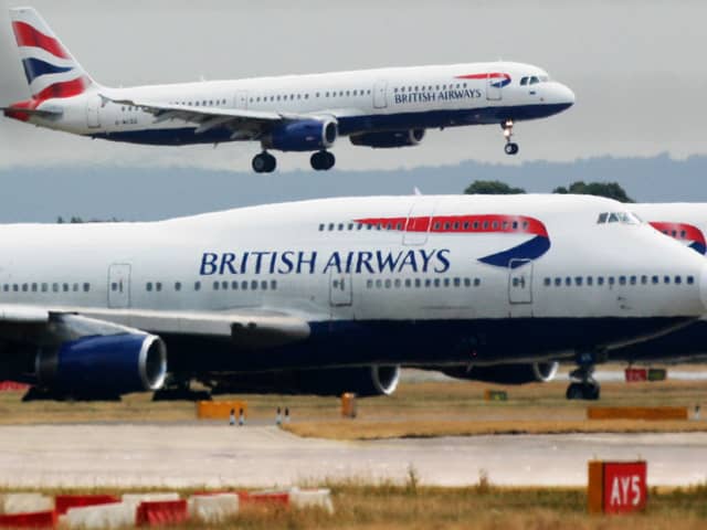 A British Airways plane lands as two other grounded planes sit on the runway at Heathrow Airport.