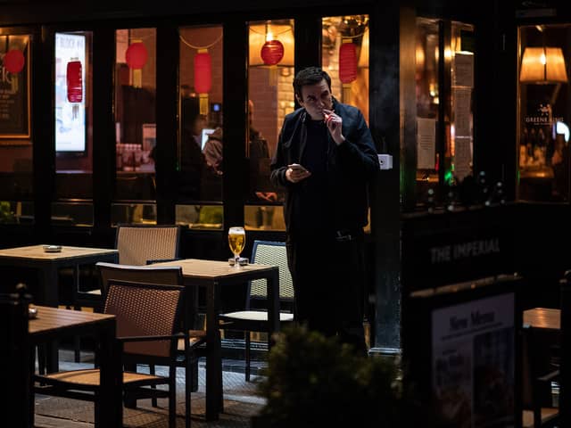 Man smokes a cigarette outside pub.