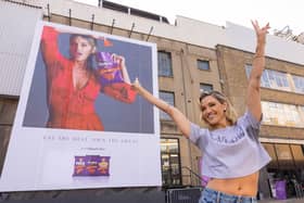 Ashley puts sweat shame to sweat fame by standing in front of her sweating billboard as the new face of Extra Flamin' Hot snacks