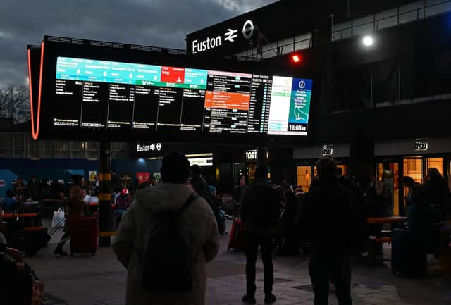 Rail travellers look at an electronic information board displaying train time information outside Euston Station in London. Photo: JUSTIN TALLIS/AFP via Getty Images