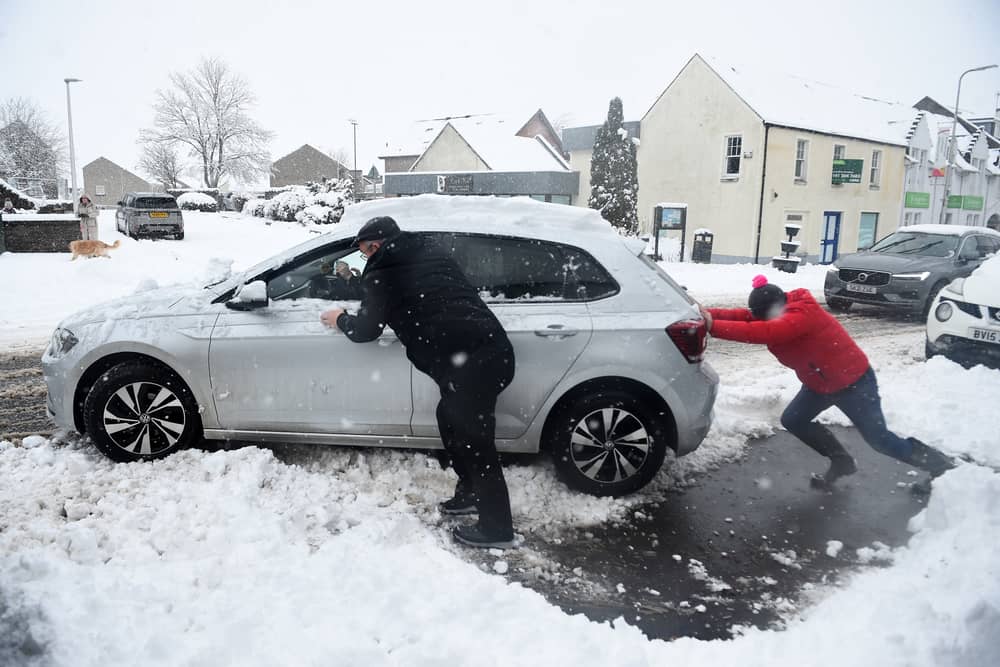 Stock image of car being pushed out of snow.