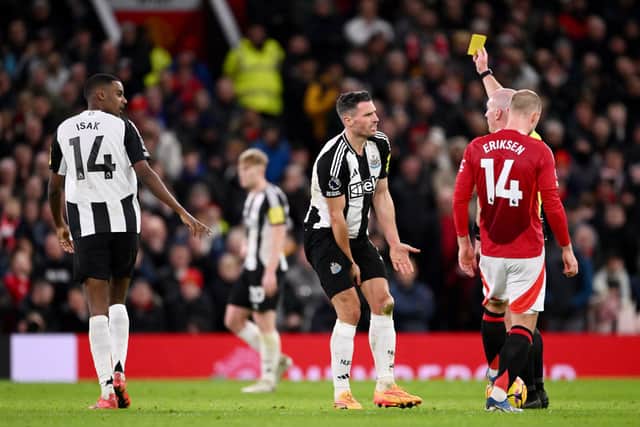 Fabian Schar of Newcastle United is shown a yellow card by referee Simon Hooper during the Premier League match between Manchester United FC and Newcastle United FC at Old Trafford on December 30, 2024 in Manchester, England. (Photo by Stu Forster/Getty Images)