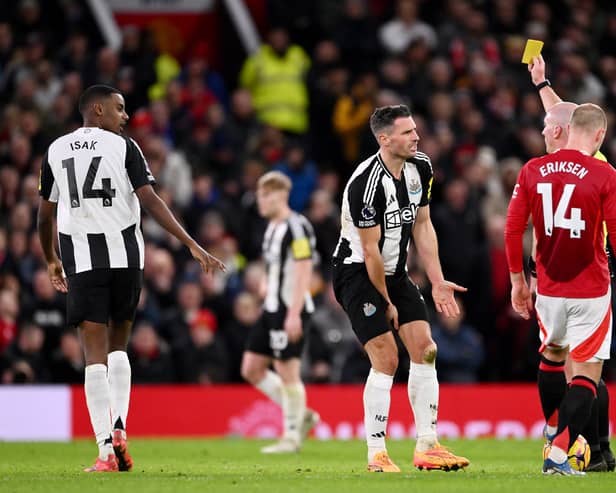 Fabian Schar of Newcastle United is shown a yellow card by referee Simon Hooper during the Premier League match between Manchester United FC and Newcastle United FC at Old Trafford on December 30, 2024 in Manchester, England. (Photo by Stu Forster/Getty Images)