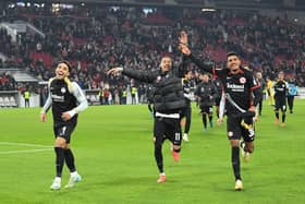 Frankfurt's Egyptian forward #07 Omar Marmoush (L), Frankfurt's French forward #11 Hugo Ekitike (C) and Frankfurt's German forward #36 Ansgar Knauff (R) celebrate with the fans after winning the German first division Bundesliga football match VfB Stuttgart vs Eintracht Frankfurt. (Photo by THOMAS KIENZLE/AFP via Getty Images)