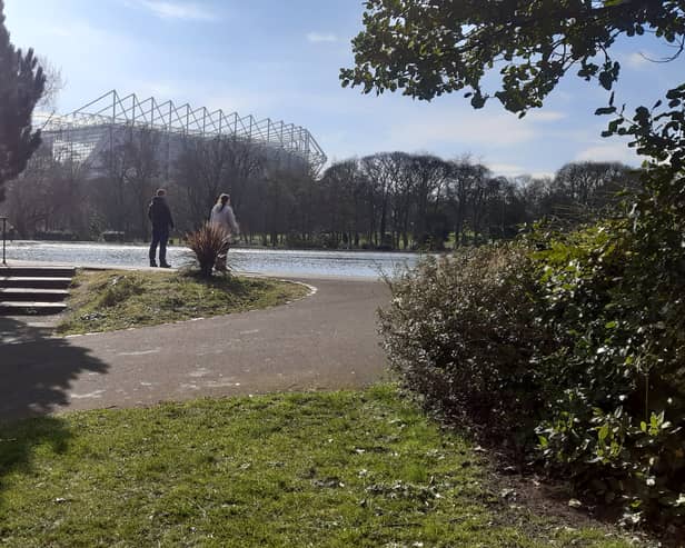 Two people in Leazes Park, Newcastle, with St James' Park in the background, where it has been rumoured Newcastle United could build a new stadium
