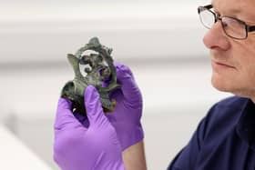 Professor Tom Moore holds a decorative copper alloy.