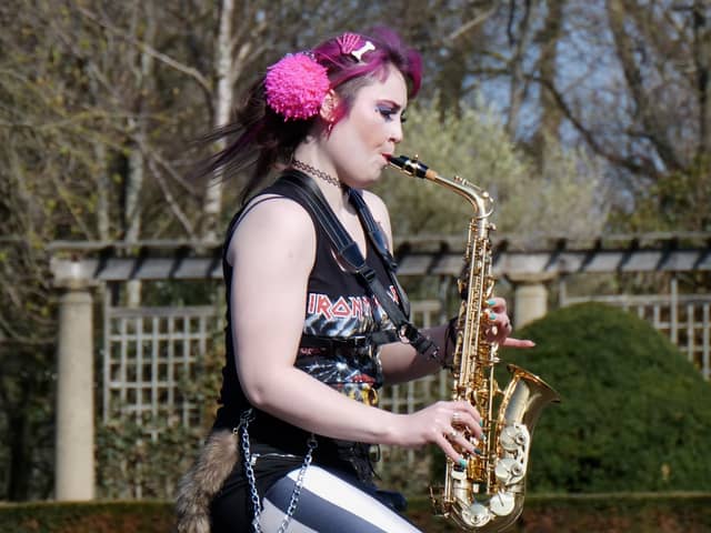 Rachel Ward unicycling while playing the saxophone