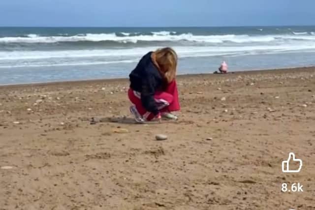 Kylie drawing a heart in the sand.