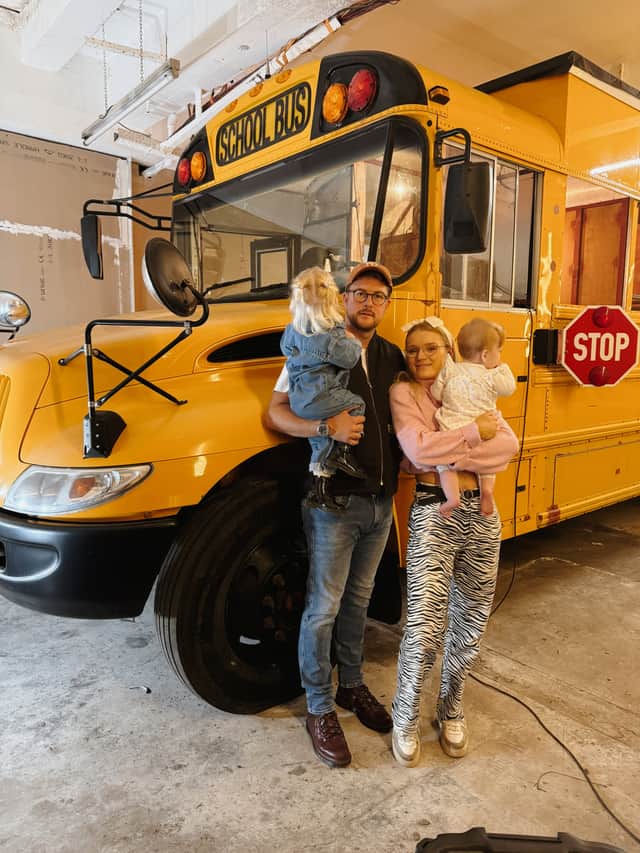 Lotti Harrison and Ty Burns with their American school bus that they are travelling around Europe in with their toddlers