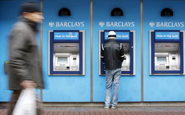 A man uses a cashpoint machine at a Barclays Bank