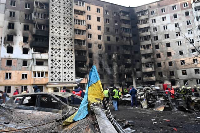 A Ukrainian flag is seen attached to a burned car at the site of a heavily damaged residential building following Russian air strike in 2025.
(Photo by YURIY DYACHYSHYN / AFP via Getty Images)