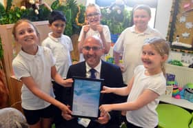 Chris Rue, Head Teacher of Epinay School, with pupils and the award granted by Sir Michael Morpurgo.
