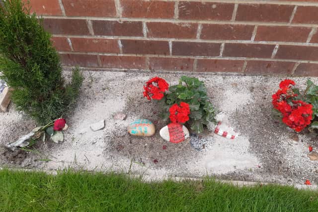 Flowers, remembrance pebbles, photographs, and people's ashes have been placed in the memorial garden.
