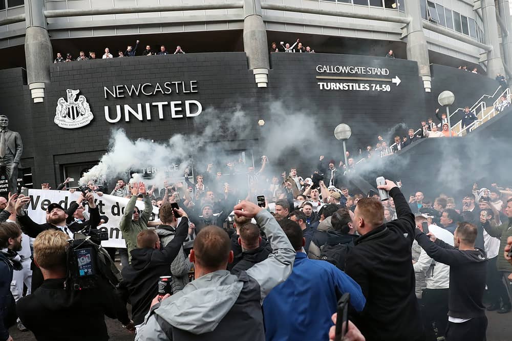 Newcastle United supporters celebrate outside the club's stadium St James' Park in Newcastle upon Tyne in northeast England on October 7, 2021, after the sale of the football club to a Saudi-led consortium was confirmed. A Saudi-led consortium completed its takeover of Premier League club Newcastle United on October 7 despite warnings from Amnesty International that the deal represented "sportswashing" of the Gulf kingdom's human rights record. (Photo by AFP via Getty Images)
