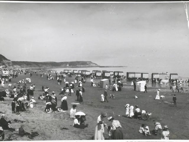 Crowds on the beach at Scarborough, North Yorkshire, with a row of bathing machines at the water's edge, 1890s.