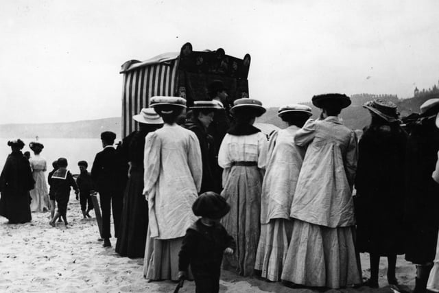 June 1908: Crowds gather to watch a Punch and Judy puppet show on the beach at Scarborough.