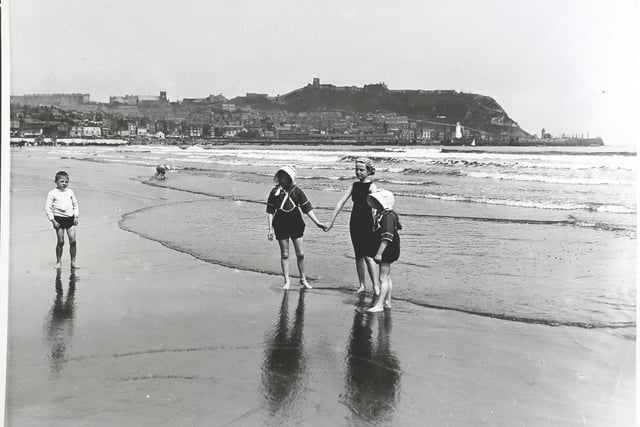 Children holding hands on the beach at Scarborough, England, circa 1913.