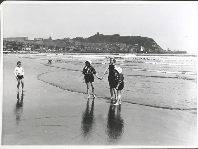Children holding hands on the beach at Scarborough, England, circa 1913.