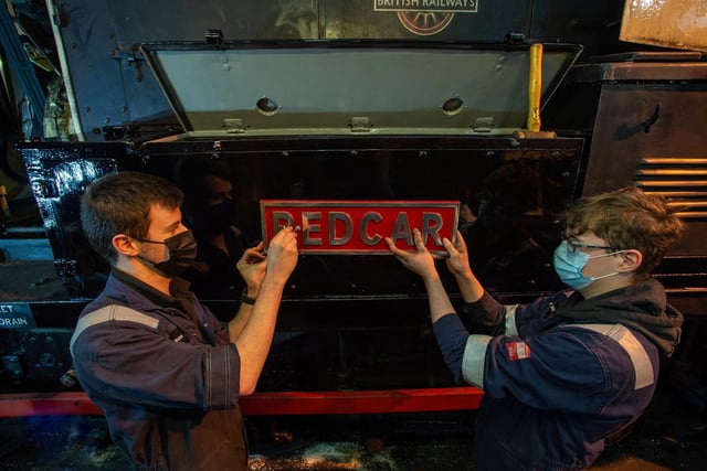 Peter Dawson and apprentice Finn Allen fitting a nameplate to a diesel shunter loco