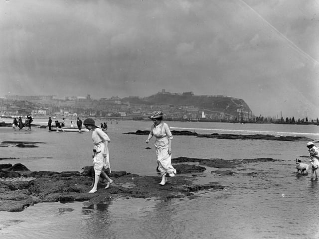 circa 1910: Bathers in the South Bay at Scarborough, a popular coastal resort in North Yorkshire. The 12th century castle stands on the cliff in the background.