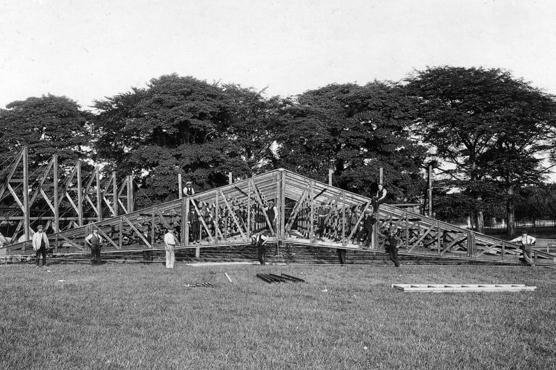 This photos shows men posing for the camera as they put up  the framework of one of the exhibition marquees.