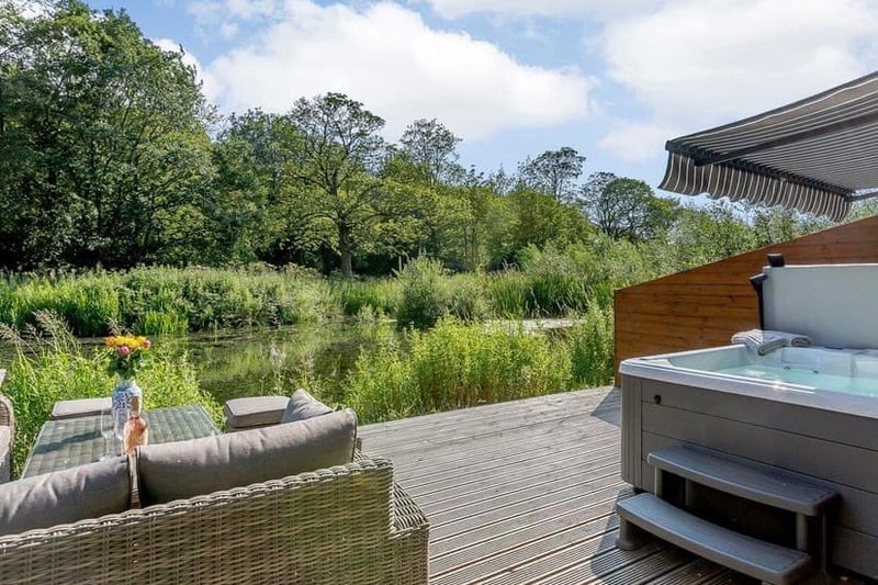 A spacious decked terrace, complete with a hot tub, overlooks the waterfront